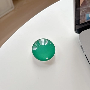 Detail of a deep emerald green crystal glass phone grip showing high-gloss mirror finish