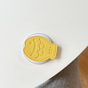 Macro detail of yellow fish-shaped leather phone socket with stitched scale patterns