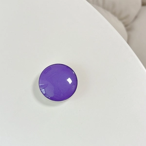Close-up of a purple crystal glass round cell phone socket stand on a white surface