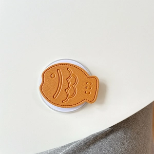 Macro view of orange fish-shaped leather phone grip with detailed lychee grain texture