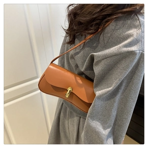 Close-up of stylish camel leather underarm bag with elegant gold metal twist lock