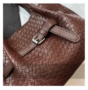 Détail d'un sac seau tressé marron foncé avec boucle métallique argentée et texture
