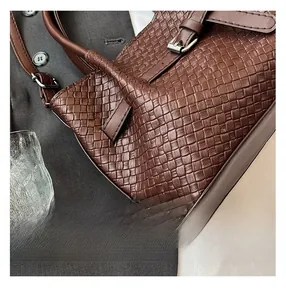 Vue détaillée de la texture en cuir tressé marron foncé sur ce sac cabas seau élégant