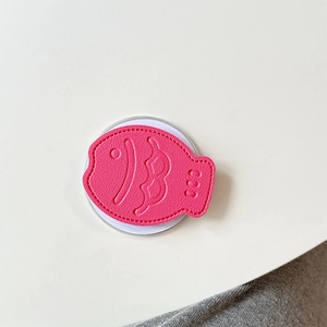 Detailed view of pink fish-shaped leather phone grip with embossed scales and fine stitching