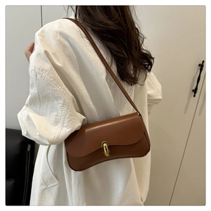 Detailed back view of a brown leather shoulder bag with gold metal clasp on a model
