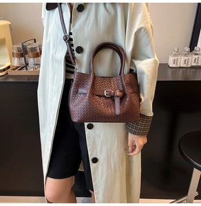 Détail du sac seau tressé marron foncé avec boucle métallique et bandoulière amovible