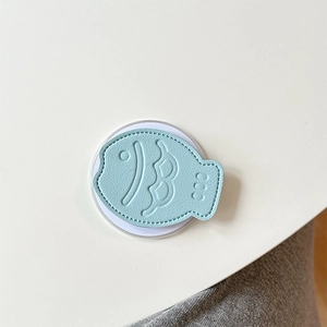 Macro shot of light blue fish-shaped leather phone grip with detailed stitching