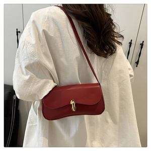 Close-up of deep red leather shoulder bag featuring a classic golden oval twist lock clasp