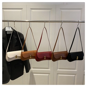 Five chic shoulder bags in cream, wine, brown, and black displayed on a white door