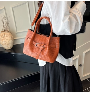 Détail du sac seau tressé caramel avec boucle argentée et bandoulière amovible