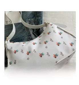 Detail of floral printed white canvas underarm bag with gold metal buckle and strap