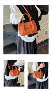 Detailed macro view of orange woven leather handbag featuring buckle strap and top handle