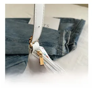 Detailed shot of gold zipper and white floral canvas strap on a summer shoulder bag