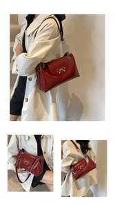 Detail of glossy red patent leather handbag with a silver metal bow buckle and chain strap