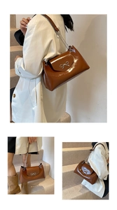 Detail of brown patent leather tote bag featuring a decorative silver metal bow accent
