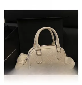 Detail of white embossed leather handbag with heart and bow motifs on black gift box