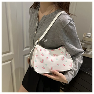Sac à bandoulière floral avec roses roses et nœuds porté par un mannequin en gris