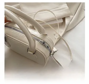Detail of cream bowling bag showing embossed floral pattern and smooth silver zipper
