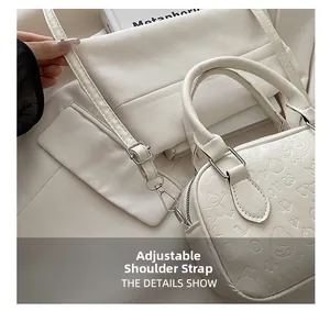 Close-up of adjustable shoulder strap buckle and heart embossed pattern on white leather bag