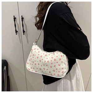 Détail du sac demi-lune en toile blanche avec motif cerises et bandoulière élégante