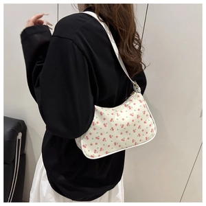 Détail du sac porté épaule tendance avec motifs de cerises rouges sur cuir blanc