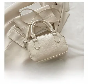 Macro view of cream-colored handbag with detailed cartoon embossing and handle