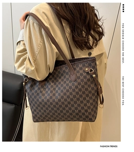 Detail of dark brown monogram tote bag with gold hardware worn with a beige trench coat