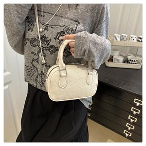 Detail of cream crossbody bag featuring cute cartoon embossed patterns and slim strap