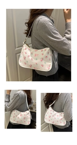 Close-up of hobo bag with pink rose and bow prints on white faux leather finish