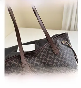 Detail of dark brown tote bag featuring all-over M monogram pattern and leather handles