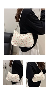 Detail view of white underarm bag featuring vibrant red cherry prints and fixed strap