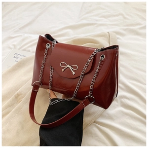 Deep red patent leather tote bag with silver bow accent and chain strap for women