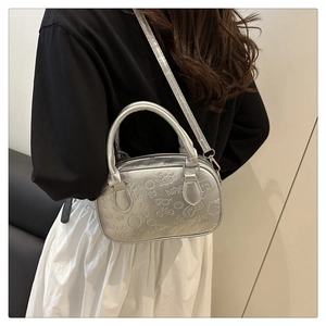 Detail of silver embossed crossbody bag featuring fun heart and bicycle patterns
