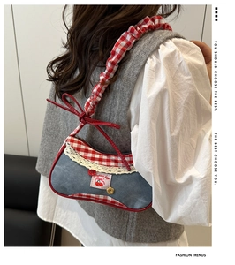 Detail of denim bag with red check trim, ruffled handle, and cherry embroidery