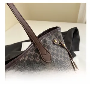 Detailed close-up of retro tote bag featuring M-pattern print and brown leather stitching