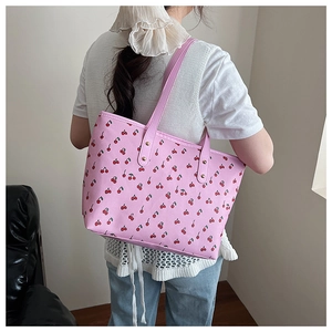 Detail of pink floral tote bag with red cherry print and reinforced gold rivet handles