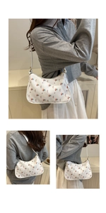 Detail showing white floral underarm bag with delicate petal print and slim shoulder strap