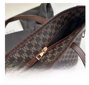 Close-up of smooth gold metal zipper and M-pattern on dark brown tote bag details
