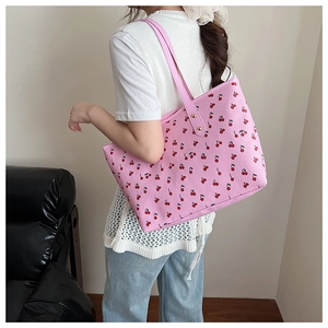 Detail of pink tote bag featuring a vibrant red cherry print and leather shoulder straps