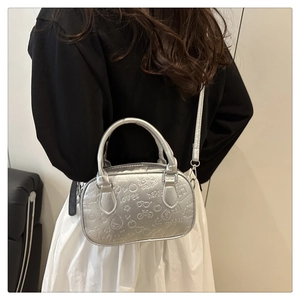 Close-up of silver crossbody bag featuring embossed cartoon motifs and metallic finish