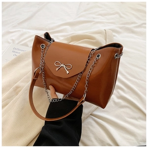 Brown leather shoulder bag with silver bow accent and metal chain strap for women