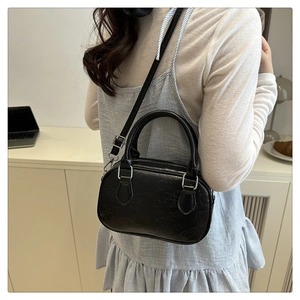 Detail of black mini crossbody bag featuring Hello Kitty embossed texture and silver hardware