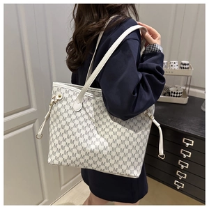 Detail of quilted tote bag with repetitive M pattern and leather shoulder straps