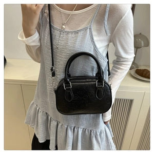 Close-up of black crossbody bag featuring embossed words like love and happy on faux leather