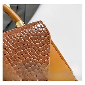 Vue détaillée du cuir texture crocodile marron et des ferrures en métal doré premium