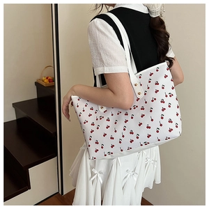 Close-up of cherry pattern on white tote bag with gold stud detail on the strap