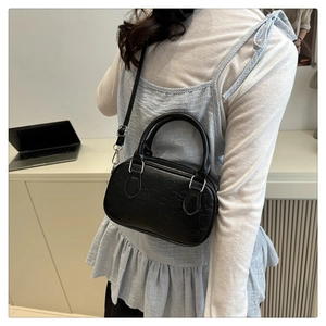 Detail of black mini crossbody bag featuring embossed cartoon patterns and dual handles