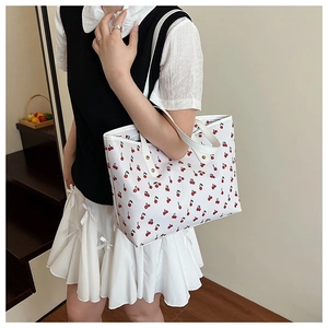 Detailed view of white shoulder bag with cherry print and metal rivets on the strap
