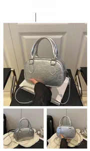Detail of silver metallic Boston bag with embossed cartoon heart patterns and top handle