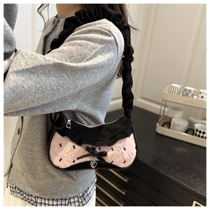 Detail of pink shoulder bag featuring black rabbit prints and a cute metal heart pendant